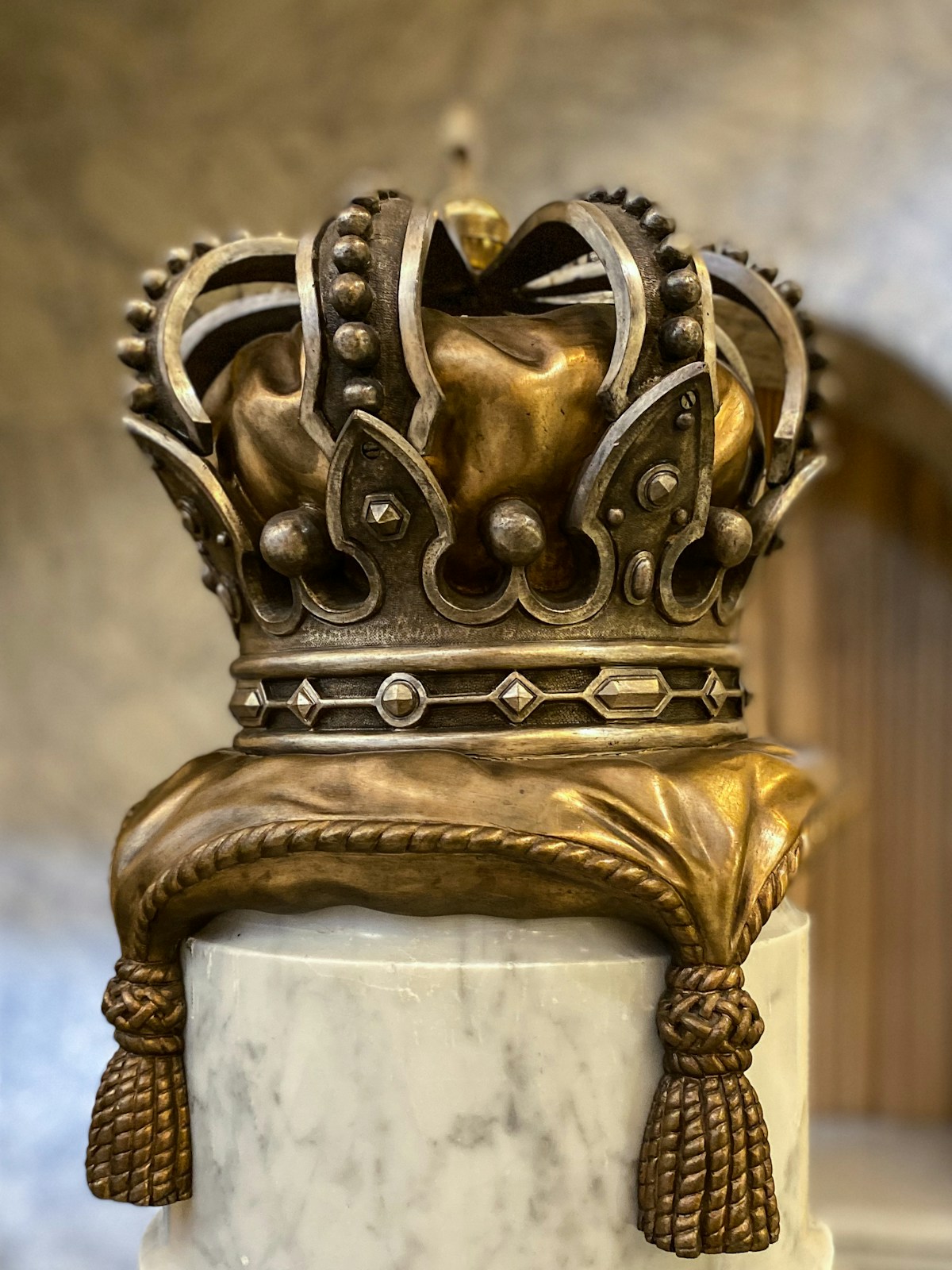 A gold crown on a marble pedestal, evoking royalty and nobility